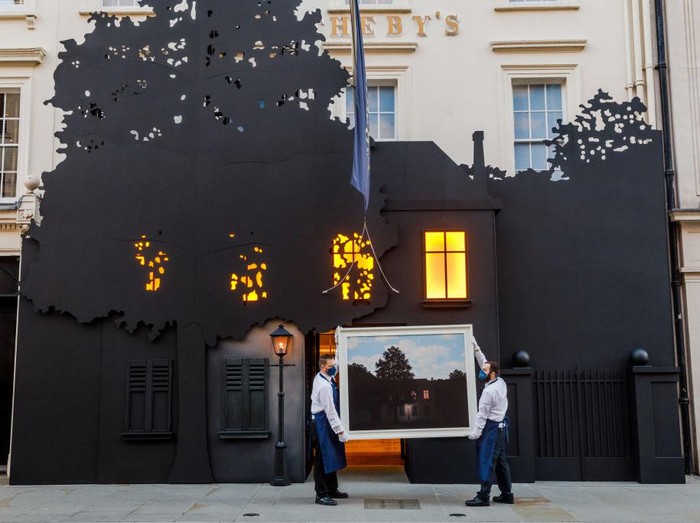LONDON, ENGLAND - FEBRUARY 23:  Sotheby’s technicians hold René Magritte’s masterwork, L’empire des lumières, outside the auction house’s New Bond Street entrance at Sotheby's on February 23, 2022 in London, England. The painting goes on sale on March 2, when it will be offered with an estimate in excess of £45 million. To coincide with its exhibition, Sotheby’s London building has been transformed to resemble the artist’s masterpiece of Surrealism. (Photo by Tristan Fewings/Getty Images for Sotheby's)