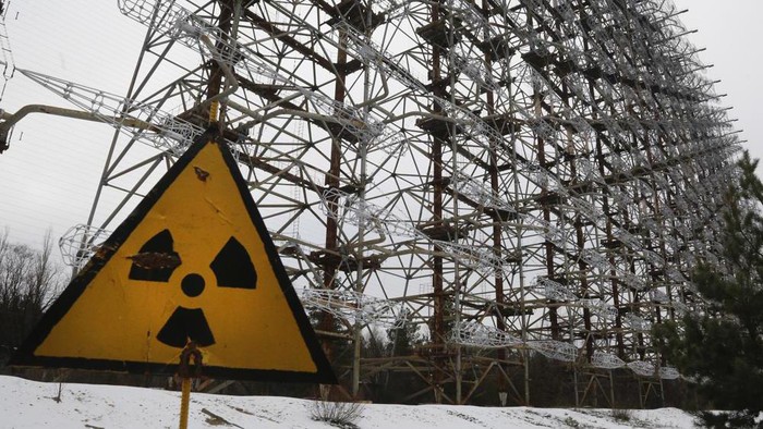 FILE - A Soviet-era top secret object Duga, an over-the-horizon radar system once used as part of the Soviet missile defense early-warning radar network, seen behind a radioactivity sign in Chernobyl, Ukraine, on Nov. 22, 2018. Among the most worrying developments on an already shocking day, as Russia invaded Ukraine on Thursday, was warfare at the Chernobyl nuclear plant, where radioactivity is still leaking from historys worst nuclear disaster 36 years ago. (AP Photo/Efrem Lukatsky, File)