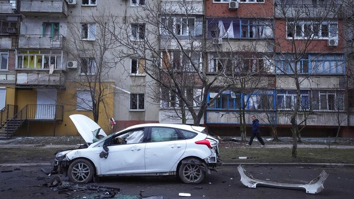 A man walks past a damaged vehicle and debris following Russian shelling in Mariupol, Ukraine, Thursday, Feb. 24, 2022. Russia has launched a barrage of air and missile strikes on Ukraine early Thursday and Ukrainian officials said that Russian troops have rolled into the country from the north, east and south. (AP Photo/Sergei Grits)