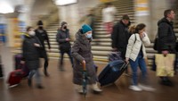 Orang-orang berjalan di kereta bawah tanah untuk mendapatkan kereta saat mereka meninggalkan kota Kyiv, Ukraina.