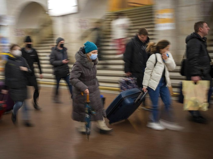 People walk in a subway to get a train as they leave the city of Kyiv, Ukraine, Thursday, Feb. 24, 2022. Russian President Vladimir Putin on Thursday announced a military operation in Ukraine and warned other countries that any attempt to interfere with the Russian action would lead to 
