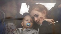 Seorang wanita menggendong bayinya di dalam bus saat mereka meninggalkan Kyiv, Ukraina.