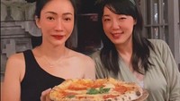 Salah satunya momen saat menikmati pizza gaya Italia ini bersama temannya. Susana berpose sambil membawa nampan berisi pizza. Foto: Instagram @susana.rahadrjo