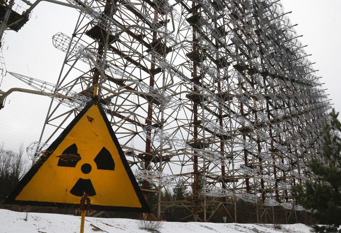 FILE - A Soviet-era top secret object Duga, an over-the-horizon radar system once used as part of the Soviet missile defense early-warning radar network, seen behind a radioactivity sign in Chernobyl, Ukraine, on Nov. 22, 2018. Among the most worrying developments on an already shocking day, as Russia invaded Ukraine on Thursday, was warfare at the Chernobyl nuclear plant, where radioactivity is still leaking from historys worst nuclear disaster 36 years ago. (AP Photo/Efrem Lukatsky, File)