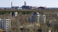 Kota Prypyat terlihat dengan latar belakang reaktor yang rusak di pembangkit listrik tenaga nuklir Chernobyl di Prypyat, Ukraina. Di latar belakang kanan adalah lengkungan baja raksasa yang sedang dibangun untuk menutupi sisa-sisa reaktor yang meledak. Foto diambil pada Selasa, (23/4/2013).
