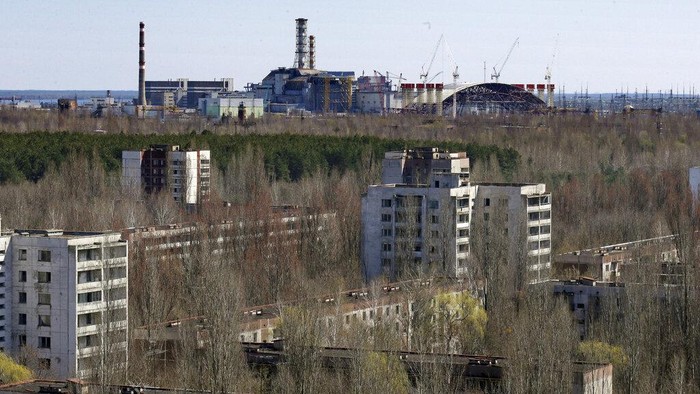 The town of Prypyat is seen against the background of the damaged reactor at the Chernobyl nuclear power plant in Prypyat, Ukraine, Tuesday, April 23, 2013. At background right is a gigantic steel-arch under construction to cover the remnants of the exploded reactor. Ukraine marks the 27th anniversary of the worlds worst nuclear disaster on April 26. (AP Photo/Efrem Lukatsky)
