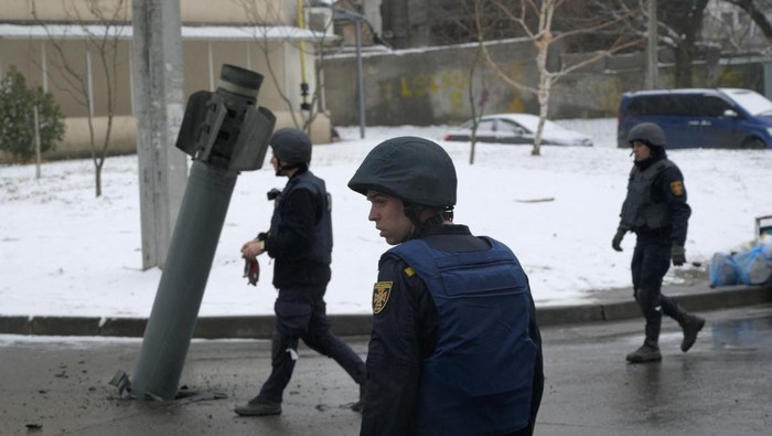 Members of the State Emergency Service of Ukraine walk towards a rocket case stuck on the driveway following recent shelling in Kharkiv, Ukraine February 25, 2022. REUTERS/Maksim Levin
