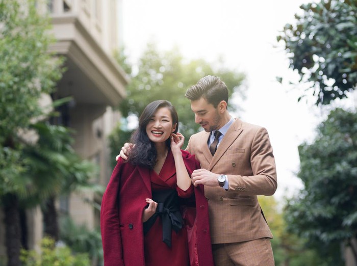 Handsome young couple,walking down the street in formal elegant clothes,showing each other how much they care for each other in a subtle way.
