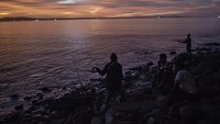 Warga memancing ikan sambil menikmati keindahan matahari terbenam. 
