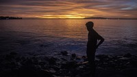 Warga melihat matahari terbenam di Pantai Taman Jaya, Pandeglang, Banten. 