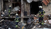 Dinding beberapa unit apartemen tampak hancur terkena ledakan rudal. Petugas darurat berada di tempat kejadian, membantu mengevakuasi warga. Jumlah korban belum jelas.