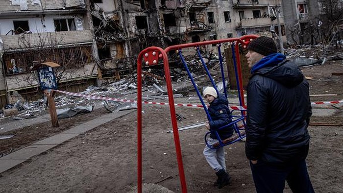 KYIV, UKRAINE - FEBRUARY 25: A boy plays on a swing in front of a damaged residential block hit by an early morning missile strike on February 25, 2022 in Kyiv, Ukraine. Yesterday, Russia began a large-scale attack on Ukraine, with Russian troops invading the country from the north, east and south, accompanied by air strikes and shelling. The Ukrainian president said that at least 137 Ukrainian soldiers were killed by the end of the first day. (Photo by Chris McGrath/Getty Images)