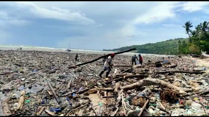 Warga memilah sampah di pinggir pantai.