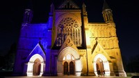 Pemandangan Katedral St Albans menyala dengan warna kuning dan biru untuk mendukung Ukraina, setelah Rusia melancarkan operasi militer besar-besaran terhadap Ukraina, di St Albans, Inggris. REUTERS/PAUL CHILDS