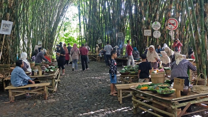 Suasana interaksi pengunjung dengan pedagang di pasar Papringan Ngaiprono, Kedu, Temanggung, Jawa Tengah, Minggu (27/2/2022). Setelah tutup selama dua tahun akibat pandemi COVID-19, wisata pendidikan dan kuliner pasar Papringan yang pembayarannya menggunakan uang bambu kembali dibuka guna memulihkan perekonomian masyarakat melalui pariwisata. ANTARA FOTO/Anis Efizudin/aww.