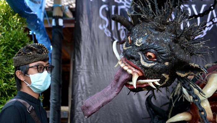 Warga berfoto di dekat Ogoh-ogoh berjudul Gerubug karya kelompok pemuda ST. Tunas Muda di Sidakarya, Denpasar, Bali, Minggu (27/2/2022). Ogoh-ogoh yang akan diarak pada malam pengrupukan atau sehari sebelum Hari Raya Nyepi yang terbuat dari bahan-bahan ramah lingkungan serta masker menggambarkan kondisi kehidupan sosial, budaya dan ekonomi masyarakat selama masa pandemi COVID-19. ANTARA FOTO/Fikri Yusuf/aww.