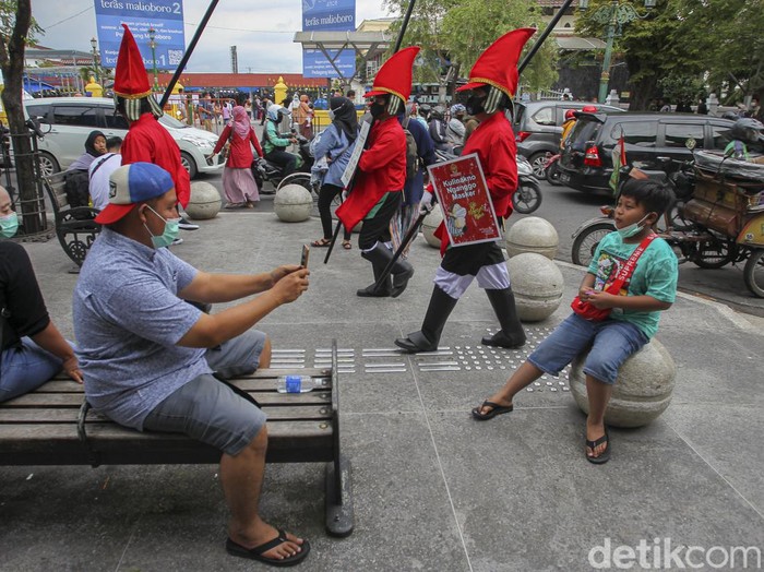 Petugas menggunakan pakaian khusus bertemakan prajurit Kraton Yogyakarta, memberikan peringatan kepada wisatawan untuk menjaga protokol kesehatan saat mengunjungi kawasan wisata Malioboro, Yogyakarta, Minggu (27/2/2022).