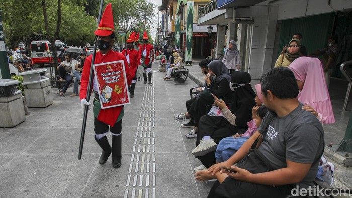 Petugas menggunakan pakaian khusus bertemakan prajurit Kraton Yogyakarta, memberikan peringatan kepada wisatawan untuk menjaga protokol kesehatan saat mengunjungi kawasan wisata Malioboro, Yogyakarta, Minggu (27/2/2022).