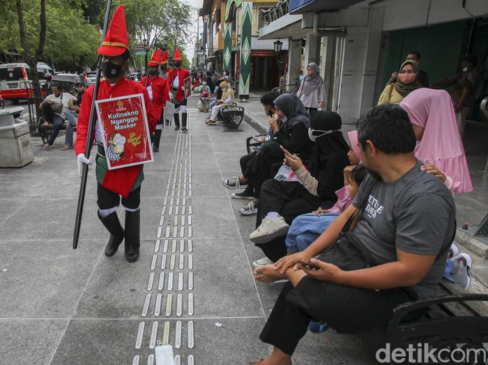 Petugas menggunakan pakaian khusus bertemakan prajurit Kraton Yogyakarta, memberikan peringatan kepada wisatawan untuk menjaga protokol kesehatan saat mengunjungi kawasan wisata Malioboro, Yogyakarta, Minggu (27/2/2022).