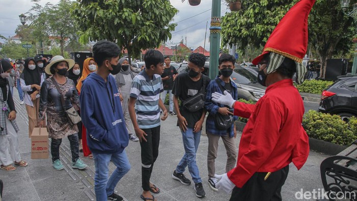 Petugas menggunakan pakaian khusus bertemakan prajurit Kraton Yogyakarta, memberikan peringatan kepada wisatawan untuk menjaga protokol kesehatan saat mengunjungi kawasan wisata Malioboro, Yogyakarta, Minggu (27/2/2022).
