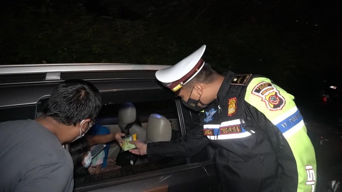 Polisi bagi-bagi makanan dan minuman ke pengendara terjebak macet di Puncak, Bogor, Minggu (27/2/2022).