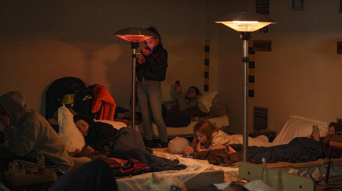 Tinggalkan Rumah, Warga Ukraina Berlindung di Bawah Tanah A woman looks at her mobile phone in a hotel underground parking turned into a bomb shelter during an air raid alert in Kyiv, Ukraine, Sunday, Feb. 27, 2022. Terrified men, women and children sought safety inside and underground, and the government maintained a 39-hour curfew to keep people off the streets as more than 150,000 Ukrainians fled to neighboring countries and the United Nations warned the number could grow to 4 million if fighting escalates.(AP Photo/Vadim Ghirda)