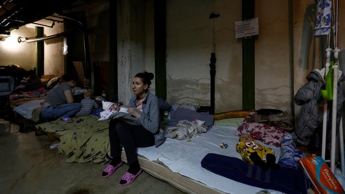 UKRAINE-CRISIS/KYIV-HOSPITAL A woman with a baby sits on a mattress in one of the shelters of Okhmadet Children's Hospital, as Russia's invasion of Ukraine continues, in Kyiv, Ukraine February 28, 2022. REUTERS/Umit Bektas