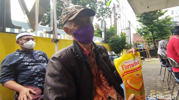 Seorang warga menerima hadiah minyak goreng saat mengikuti vaksinasi yang digelar Muhammadiyah di Semarang, Senin (28/2/2022).