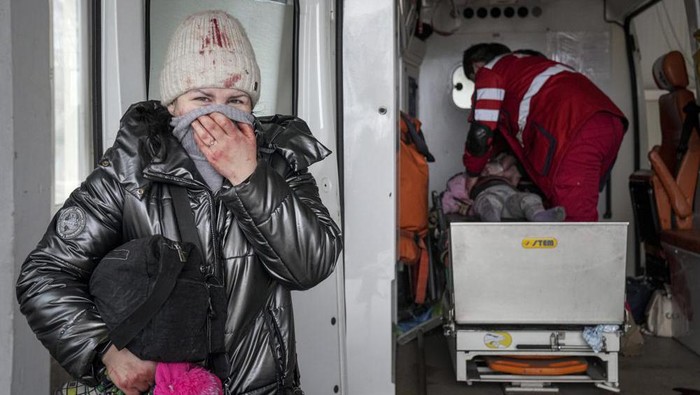 A woman reacts as paramedics perform CPR on a girl who was injured during shelling, at city hospital of Mariupol, eastern Ukraine, Sunday, Feb. 27, 2022. The girl did not survive. (AP Photo/Evgeniy Maloletka)
