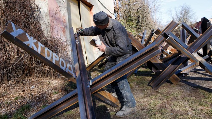 A local resident paints anti-tank obstacles built to defend the city, after Russia launched a massive military operation against Ukraine, in Uzhhorod, Ukraine February 27, 2022. The inscription reads: 
