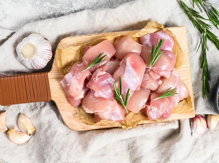 chicken thigh fillet cut into cubes. Gray background. Top view.