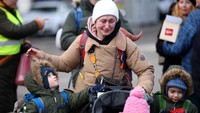 Seorang wanita menangis saat membawa kedua anaknya melarikan diri dari invasi Rusia ke Ukraina di perbatasan yang berada di kawasan Siret, Rumania, Senin (28/2/2022). (REUTERS/STOYAN NENOV)