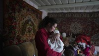 Anastasia Manha, 23, menidurkan putranya yang berusia 2 bulan, Mykyta, usai bentrok bersenjata di Novognativka, Ukraina timur, Minggu, (20/2/2022). (AP Photo/Evgeniy Maloletka)