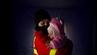 Petugas menggendong bayi di perbatasan Ukraina-Rumania, Sabtu (26/2/2022). Bayi tersebut dibawa oleh keluarga yang mengungsi akibat invasi Rusia. (AP Photo/Andreea Alexandru)