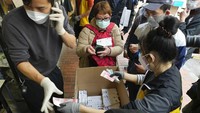 Pelanggan yang memakai masker membeli alat tes antigen COVID-19 di sebuah pasar di Hong Kong.