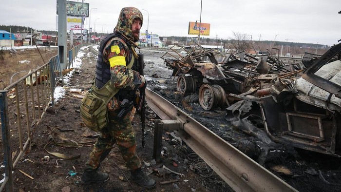 EDS NOTE: GRAPHIC CONTENT - A man looks at a Russian soldiers body lying next to a military vehicle on a road in the town of Bucha close to Kyiv, Ukraine, Tuesday, 2022. Russia on Tuesday stepped up shelling of Kharkiv, Ukraines second-largest city, pounding civilian targets there. Casualties mounted and reports emerged that more than 70 Ukrainian soldiers were killed after Russian artillery recently hit a military base in Okhtyrka, a city between Kharkiv and Kyiv, the capital. (AP Photo/Serhii Nuzhnenko)