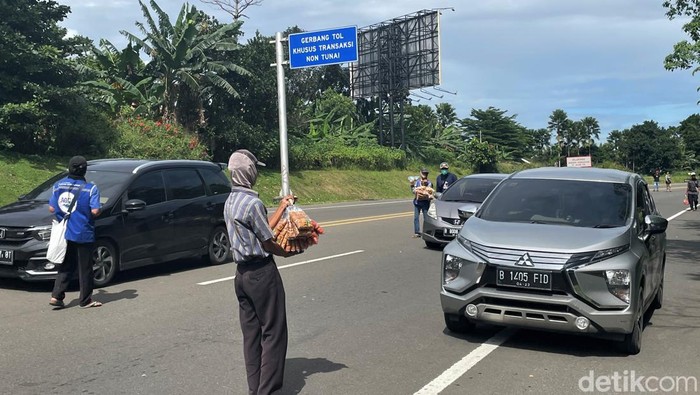 Ramainya kawasan Puncak, Bogor, saat liburan dimanfaatkan para pedagang asongan untuk meraup cuan. Beragam dagangan dijajakan kepada pengendara yang melintas.