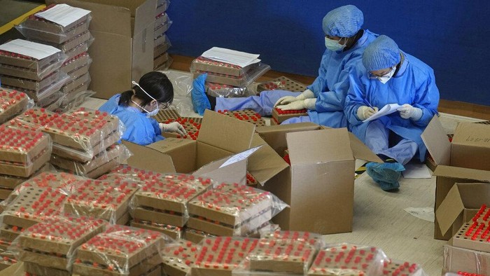 Health workers from mainland China pass by hundreds of samples from Hong Kong residents to be tested for the coronavirus at an inflatable mobile testing lab in a sports center in Hong Kong Tuesday, March 1, 2022. Hong Kong has ramped up its testing capacity with the help of the mobile laboratories, as the city grapples with tens of thousands of COVID-19 cases daily. (AP Photo/Vincent Yu)
