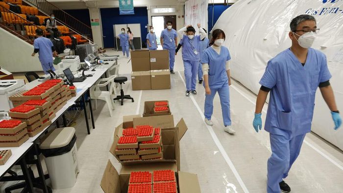 Health workers from mainland China pass by hundreds of samples from Hong Kong residents to be tested for the coronavirus at an inflatable mobile testing lab in a sports center in Hong Kong Tuesday, March 1, 2022. Hong Kong has ramped up its testing capacity with the help of the mobile laboratories, as the city grapples with tens of thousands of COVID-19 cases daily. (AP Photo/Vincent Yu)