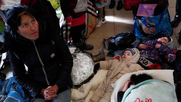 Ukraina Diserang Rusia, 1 Juta Warganya Jadi Pengungsi Children sleep next to a woman sitting on the floor at the train station, after fleeing Russia's invasion of Ukraine, in Zahony, Hungary March 3, 2022. REUTERS/Bernadett Szabo