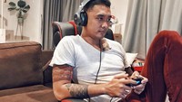 Santai di rumah, Uus menikmati waktu dengan main game sambil ditemani dengan segelas kopi dan minuman berenergi. Foto: Instagram @uusbiasaaja