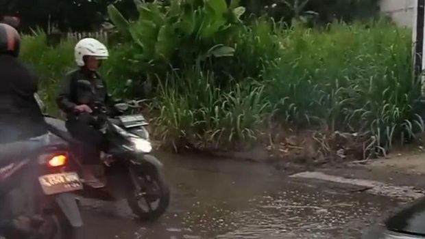 Permukaan Jalan Pengasinan Depok rusak. Saat hujan, lubang-lubang di jalan tertutup air sehingga tak terlihat pengendara.