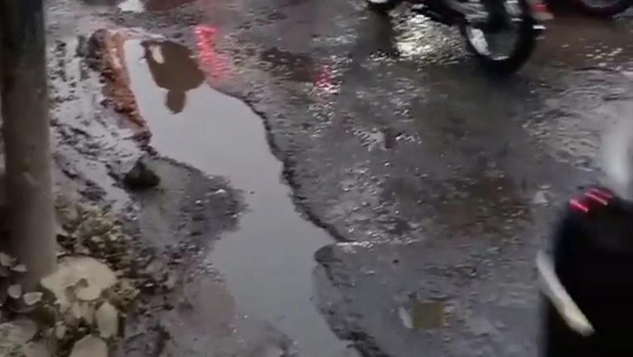 Permukaan Jalan Pengasinan Depok rusak. Saat hujan, lubang-lubang di jalan tertutup air sehingga tak terlihat pengendara.