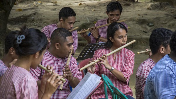 Sejumlah seniman Molucca Bamboowind Orchestra (MBO) meniup suling bambu saat konser di Dusun Tuni, Kota Ambon, Maluku, Jumat (4/3/2022).