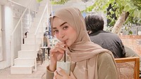 Momen lain Dinan Fajrina saat menikmati segelas kopi di kafe. Ia berpose manis sambil memegang gelas berisikan kopi. Foto: Instagram @dinanfajrina