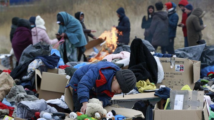 A child collects toys near a clothes donation point as refugees fleeing conflict in Ukraine arrive at the Medyka border crossing in Poland, Monday, Feb. 28, 2022. (AP Photo/Visar Kryeziu)
