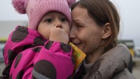 Wajah sedih seorang Ibu menggendong anak bayinya usai melarikan diri dari perang di Ukraina. Kini mereka bersatu kembali dengan keluarga mereka setelah melintasi perbatasan di Medyka, Polandia, Selasa, 1 Maret 2022. Foto: AP/Markus Schreiber