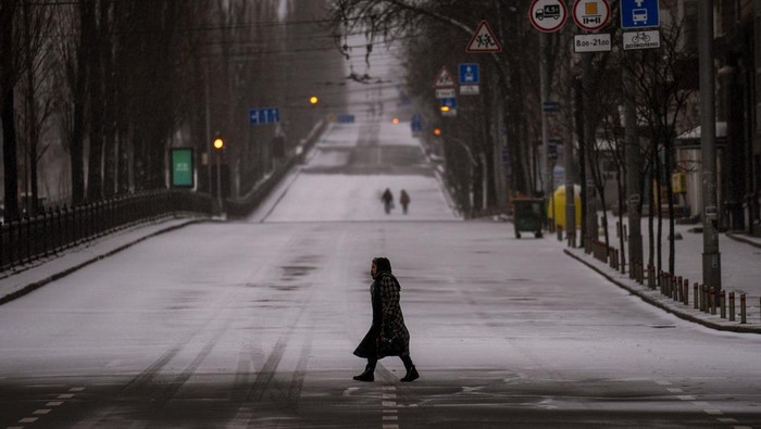 People walk along an empty road during curfew, in Kyiv, Ukraine, Tuesday, March 1, 2022. (AP Photo/Emilio Morenatti)