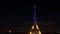 Prancis juga menyerukan solidaritas untuk Ukraina di Paris. Refleksi sorot lampu berwarna biru-kuning khas Bendera Ukraina mejeng di Menara Eiffel. REUTERS/Benoit Tessier.