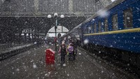 Sebuah keluarga Ukraina menaiki Dnipro-Truskavets di stasiun kereta api Lviv, Minggu, 27 Februari 2022, di Lviv, Ukraina Barat. Mereka harus mengungsi keluar dari wilayah perang. Foto: AP/Bernat Armangue